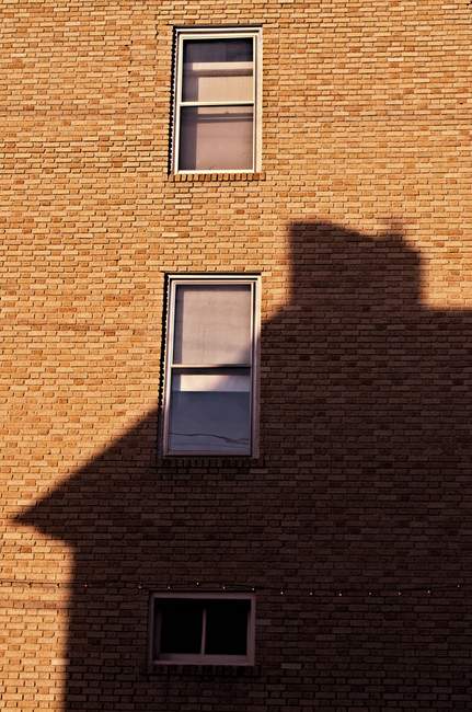 A house casts its shadow on the brick across the street